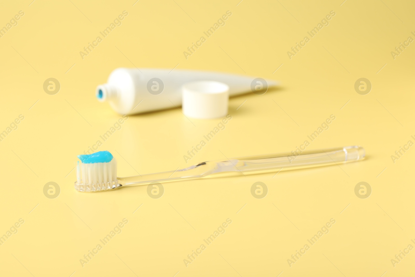 Photo of Toothbrush with toothpaste and tube on yellow background