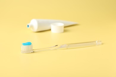 Photo of Toothbrush with toothpaste and tube on yellow background