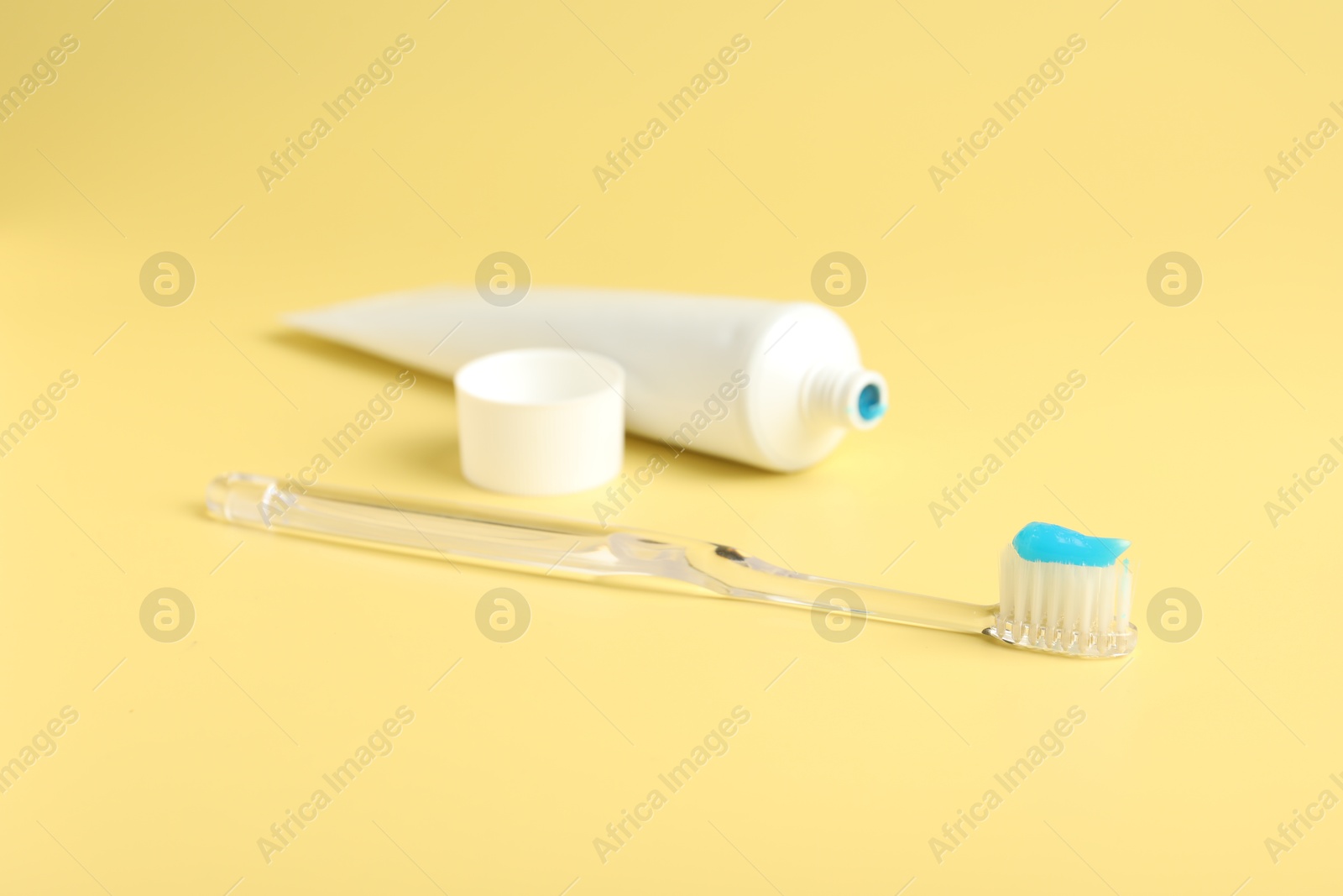 Photo of Toothbrush with toothpaste and tube on yellow background