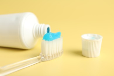 Photo of Toothbrush with toothpaste and tube on yellow background, closeup