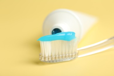 Photo of Toothbrush with toothpaste and tube on yellow background, closeup