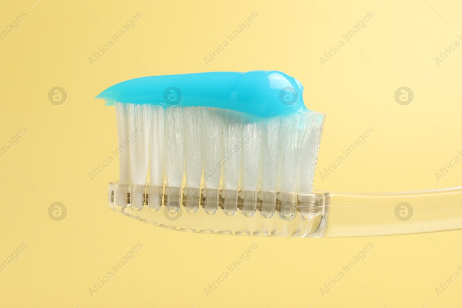 Photo of Toothbrush with toothpaste on yellow background, closeup