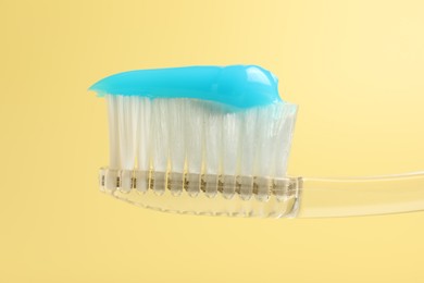 Photo of Toothbrush with toothpaste on yellow background, closeup