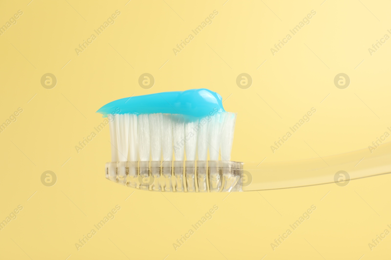 Photo of Toothbrush with toothpaste on yellow background, closeup