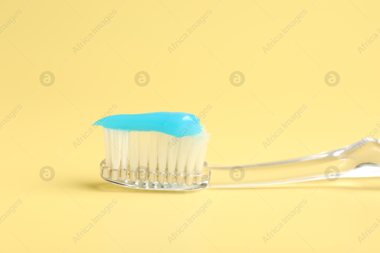 Toothbrush with toothpaste on yellow background, closeup Photo of Toothbrush with toothpaste on yellow background, closeup