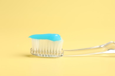 Photo of Toothbrush with toothpaste on yellow background, closeup