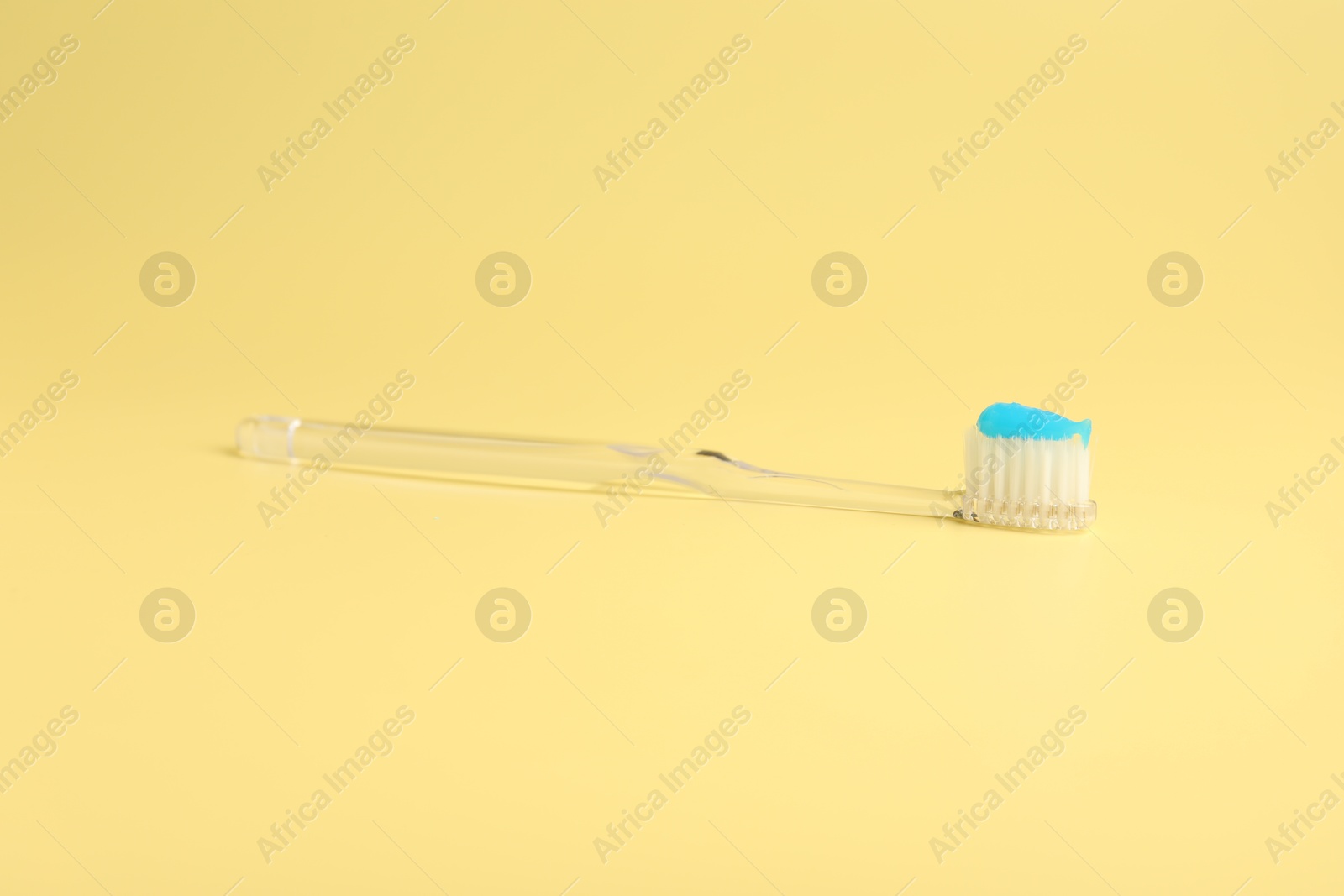 Photo of Toothbrush with toothpaste on yellow background, closeup