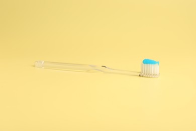 Photo of Toothbrush with toothpaste on yellow background, closeup