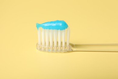 Photo of Toothbrush with toothpaste on yellow background, closeup