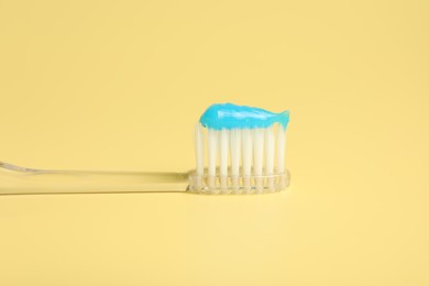 Photo of Toothbrush with toothpaste on yellow background, closeup