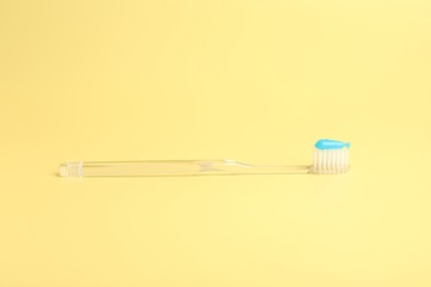 Photo of One toothbrush with toothpaste on yellow background