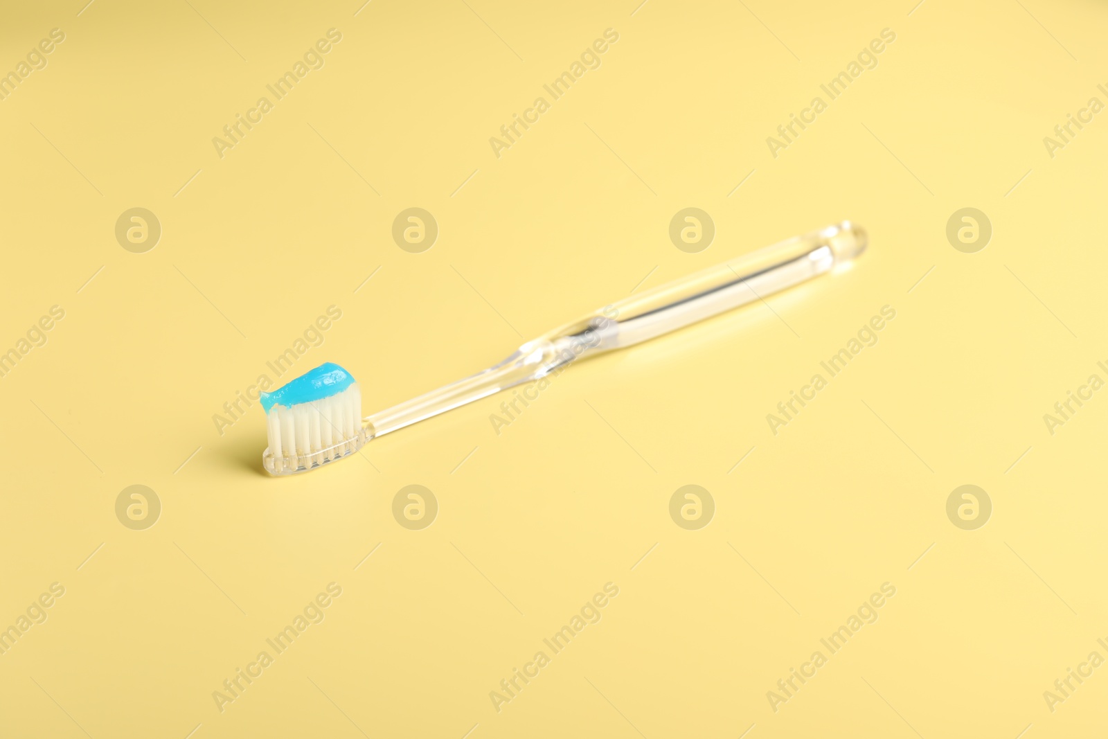 Photo of Toothbrush with toothpaste on yellow background, closeup