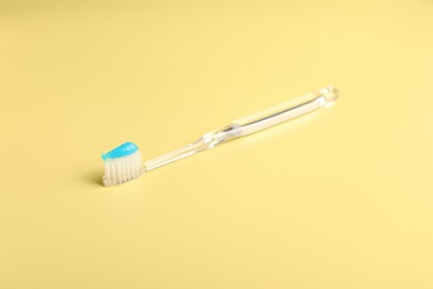 Photo of Toothbrush with toothpaste on yellow background, closeup