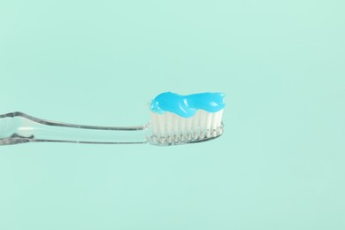 Photo of Toothbrush with toothpaste on light blue background, closeup