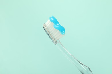 Photo of Toothbrush with toothpaste on light blue background, closeup