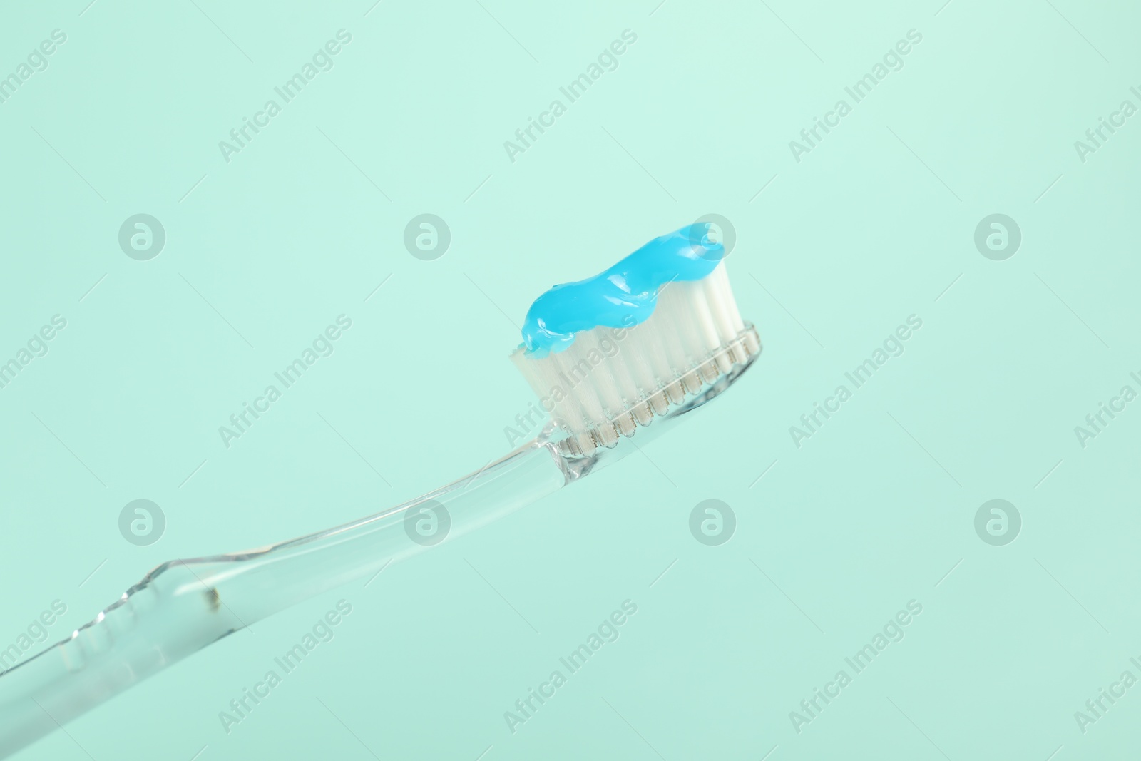 Photo of Toothbrush with toothpaste on light blue background, closeup