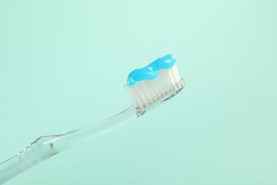 Photo of Toothbrush with toothpaste on light blue background, closeup