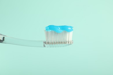 Photo of Toothbrush with toothpaste on light blue background, closeup