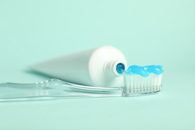 Photo of Toothbrush with toothpaste and tube on light blue background, closeup