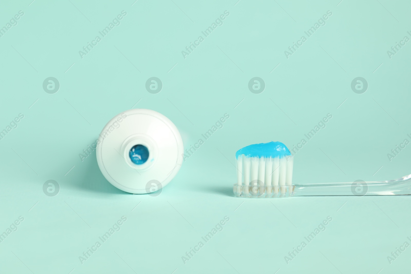 Photo of Toothbrush with toothpaste and tube on light blue background