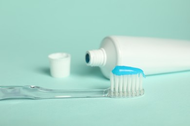 Photo of Toothbrush with toothpaste and tube on light blue background, closeup