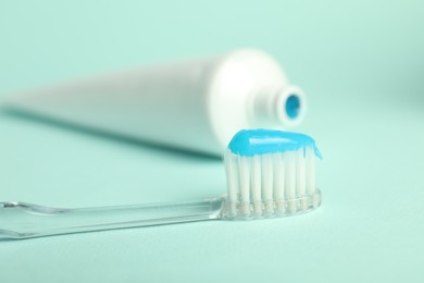 Photo of Toothbrush with toothpaste and tube on light blue background, closeup