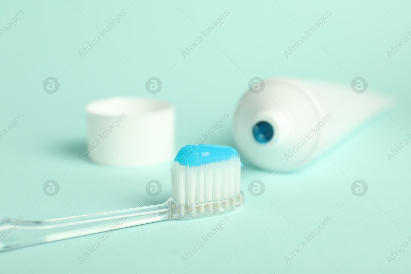 Photo of Toothbrush with toothpaste and tube on light blue background, closeup