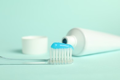 Photo of Toothbrush with toothpaste and tube on light blue background, closeup