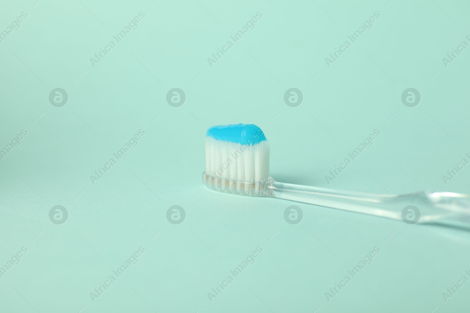 Photo of Toothbrush with toothpaste on light blue background, closeup. Space for text