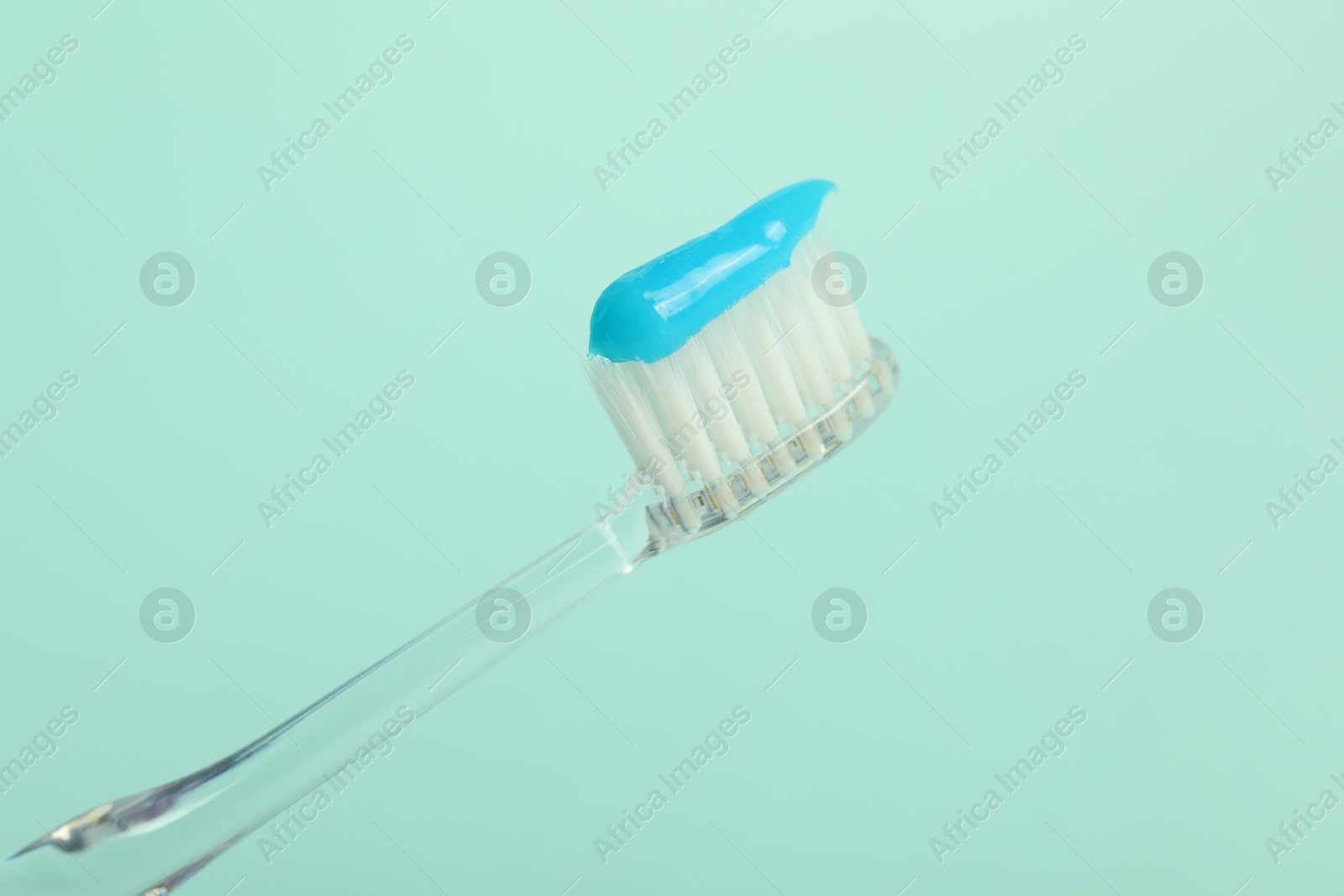 Photo of Toothbrush with toothpaste on light blue background, closeup