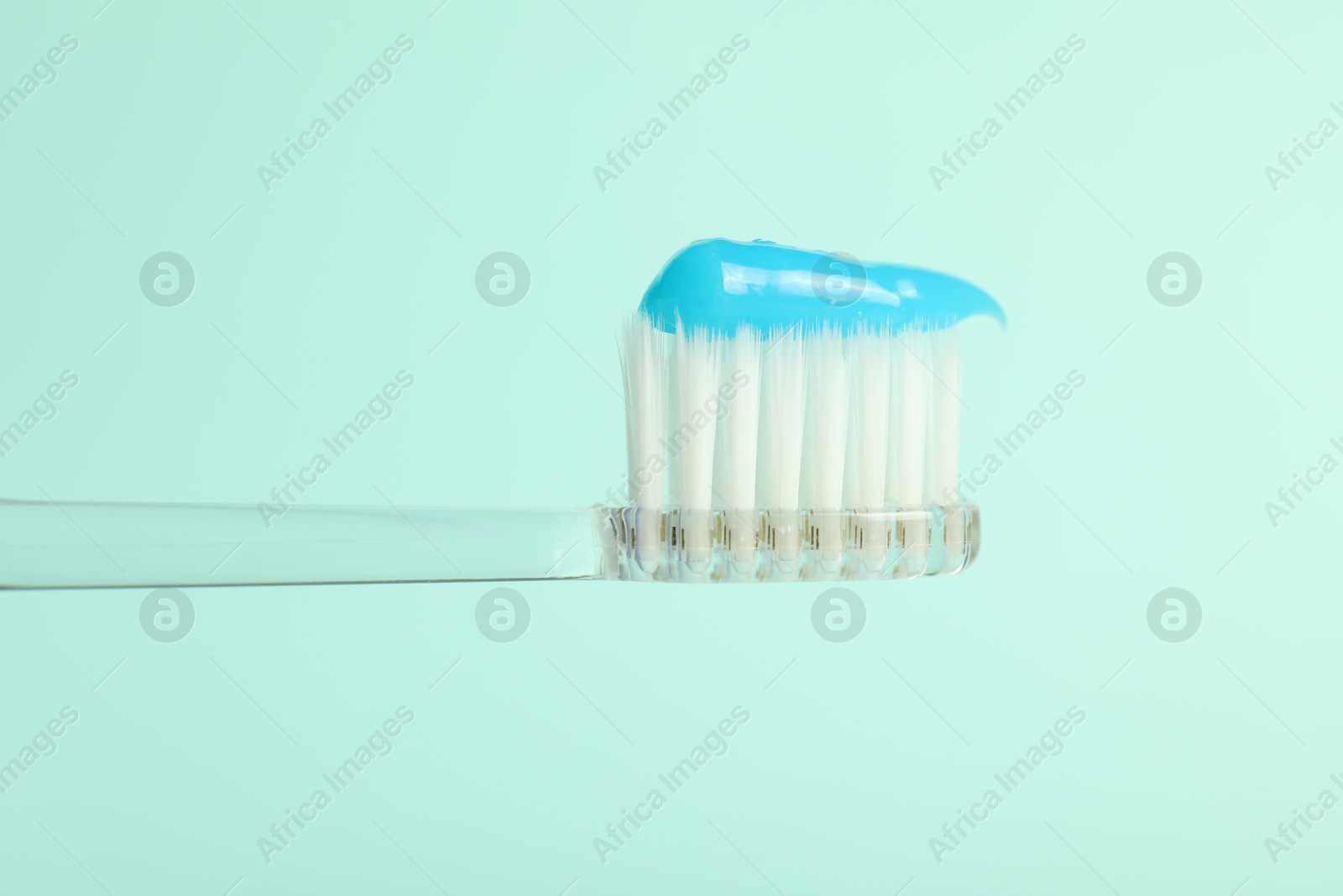 Photo of Toothbrush with toothpaste on light blue background, closeup