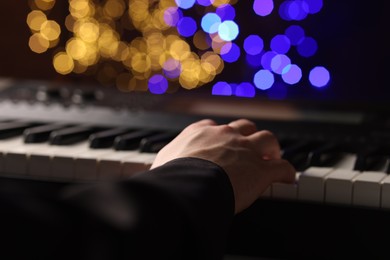 Photo of Man playing piano against blurred lights, closeup. Bokeh effect