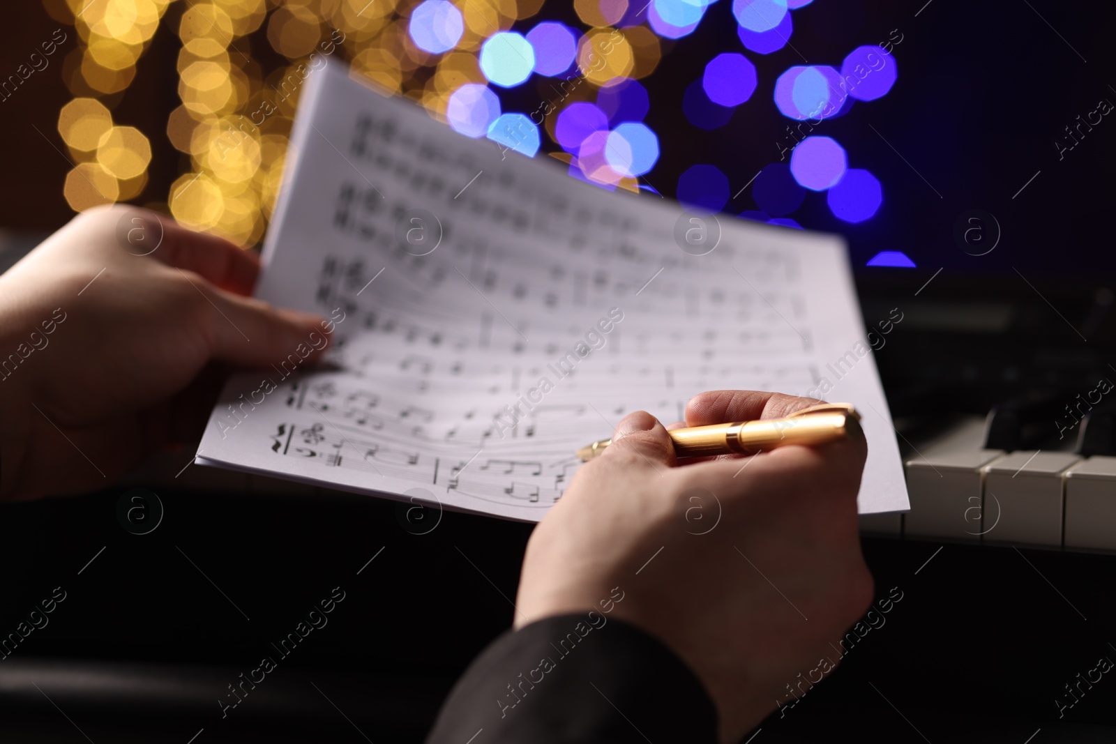 Photo of Man with notes at piano against blurred lights, closeup. Bokeh effect