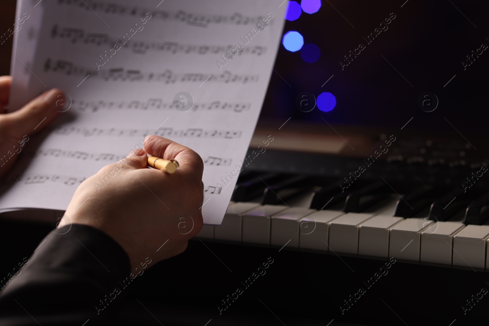 Photo of Man with notes at piano against blurred lights, closeup. Bokeh effect