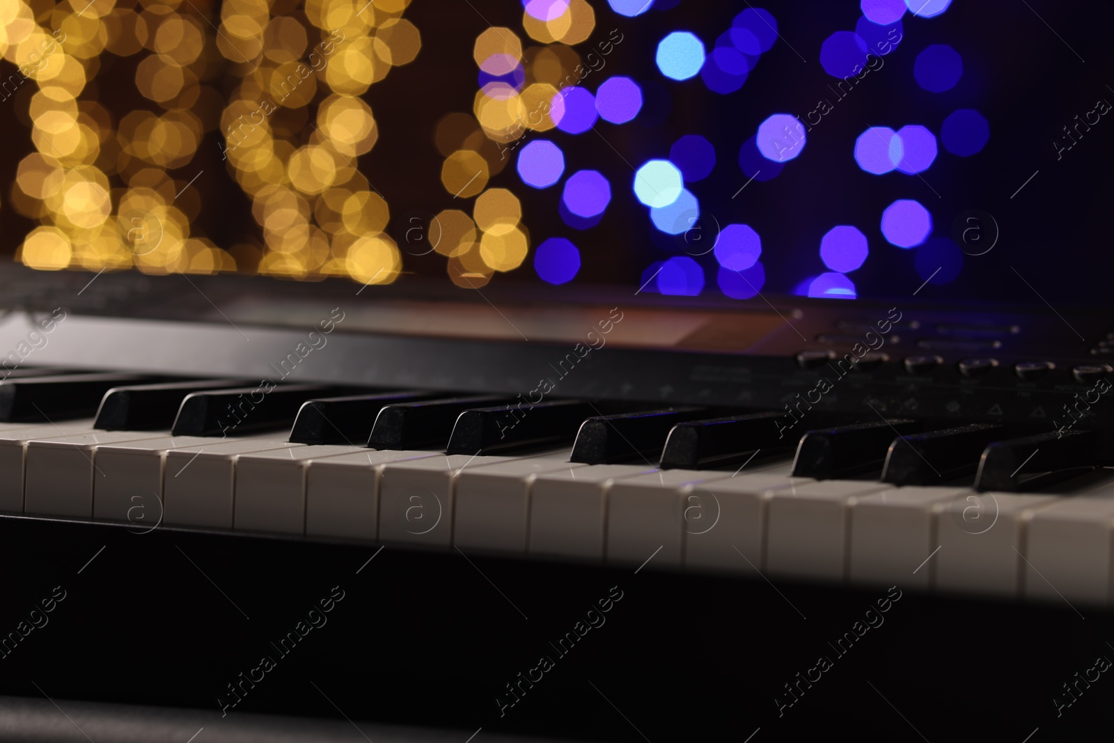 Photo of Piano against blurred lights, closeup. Bokeh effect