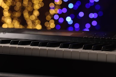 Photo of Piano against blurred lights, closeup. Bokeh effect