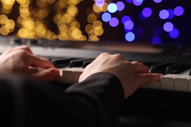 Photo of Man playing piano against blurred lights, closeup. Bokeh effect