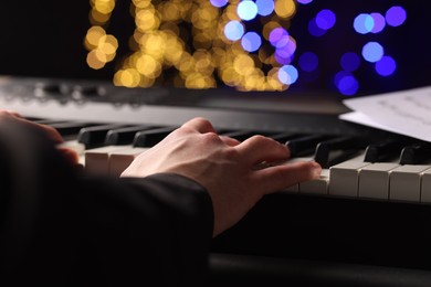 Photo of Man playing piano against blurred lights, closeup. Bokeh effect