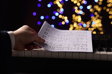 Photo of Man playing piano against blurred lights, closeup. Bokeh effect