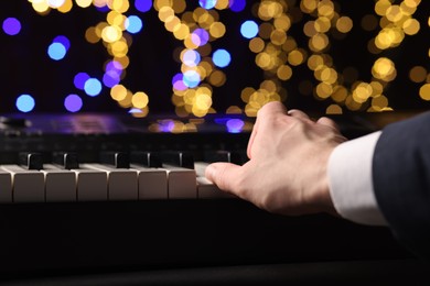 Photo of Man playing piano against blurred lights, closeup. Bokeh effect