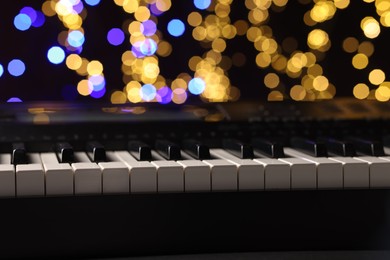 Photo of Piano against blurred lights, closeup. Bokeh effect