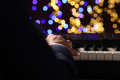 Photo of Man playing piano against blurred lights, closeup. Bokeh effect