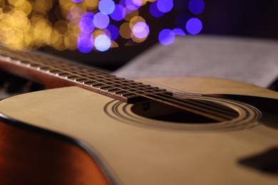 Photo of Guitar against blurred lights, closeup. Bokeh effect