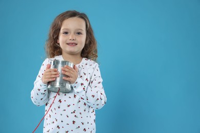 Photo of Girl using tin can telephone on blue background. Space for text