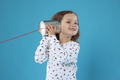 Photo of Girl using tin can telephone on blue background