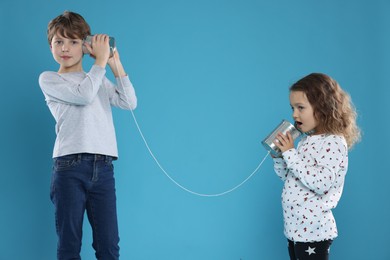 Photo of Boy and girl talking on tin can telephone against blue background