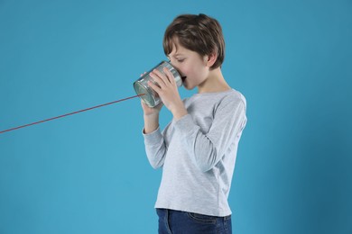 Photo of Boy using tin can telephone on blue background