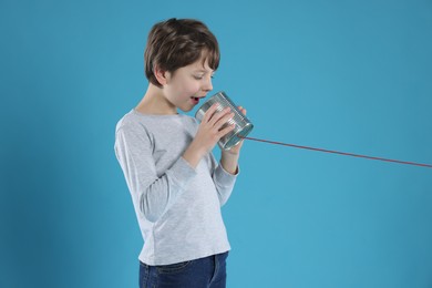 Photo of Boy using tin can telephone on blue background