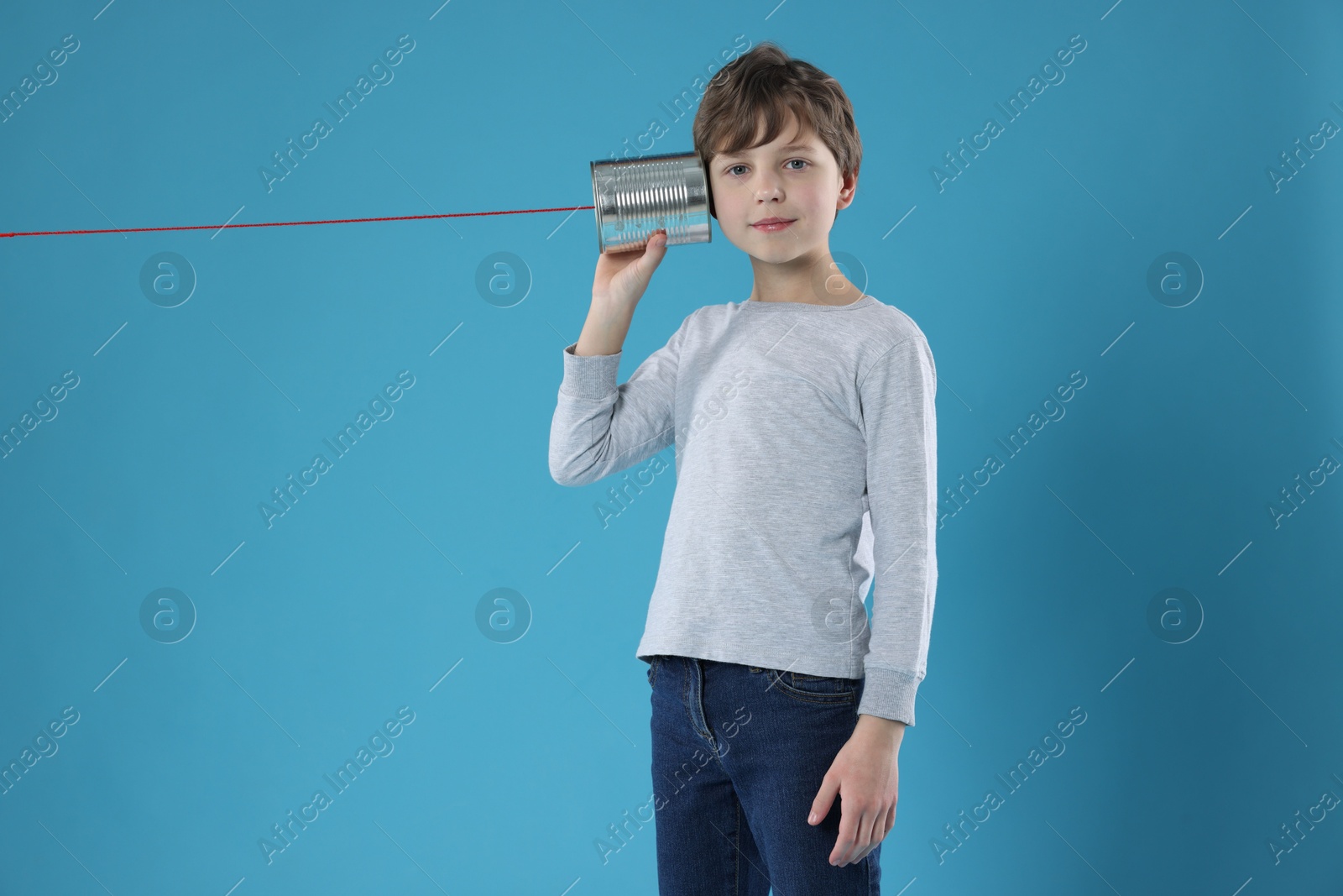 Photo of Boy using tin can telephone on blue background