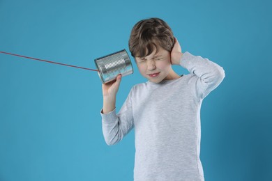 Photo of Boy using tin can telephone on blue background